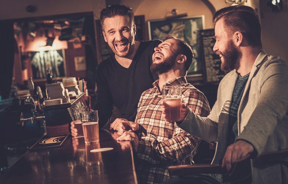 Friends laughing and drinking beer at a pub